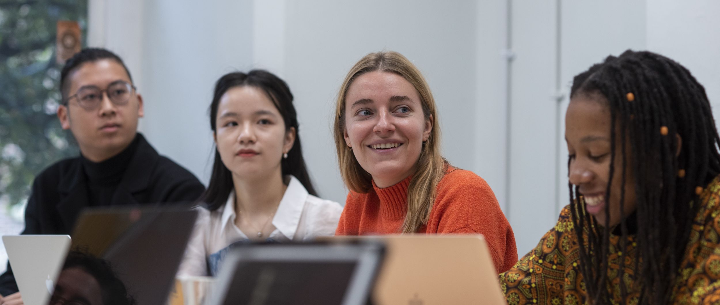 Four students in a seminar room looking at laptops