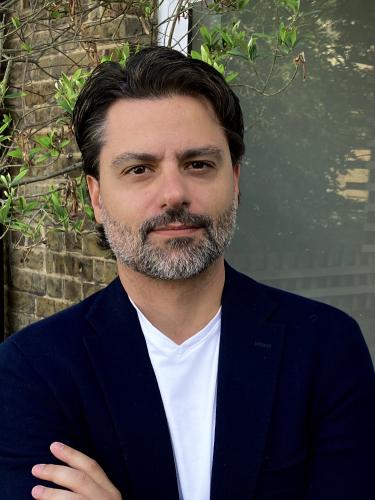 felipe krause has short dark hair and a grey beard. He's wearing a white t shirt under a black jacket