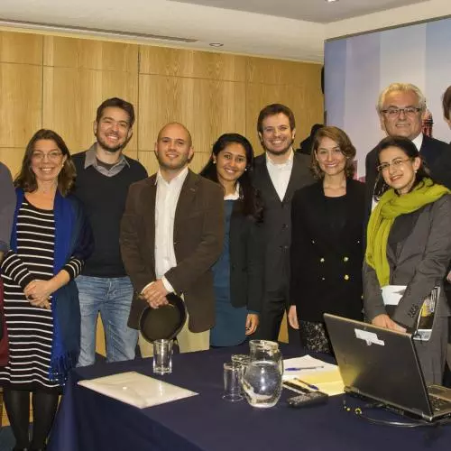 A group of people standing around an event table, smiling. 2018