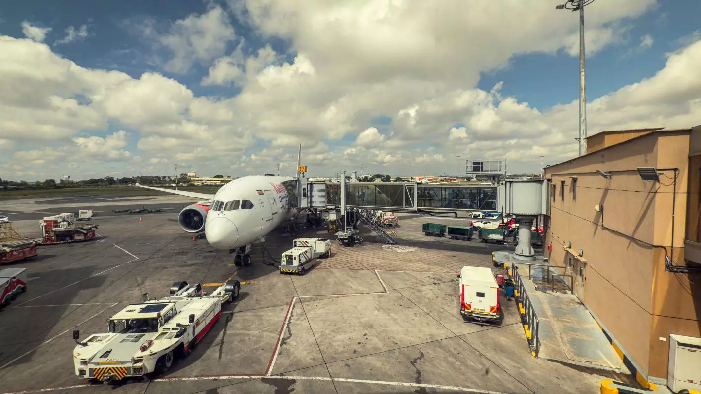 Commercial Airplane with Luggage and Service Vehicles at Jomo Kenyatta International Airport in Nairobi 