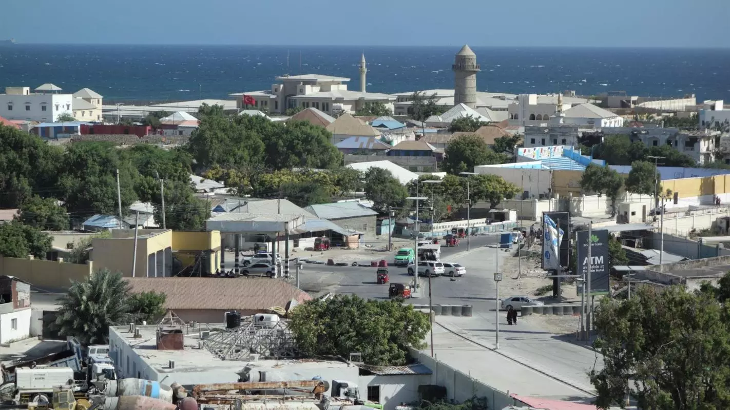 An aerial shot of Mogadischu. A road runs through a town heading towards the ocean. 