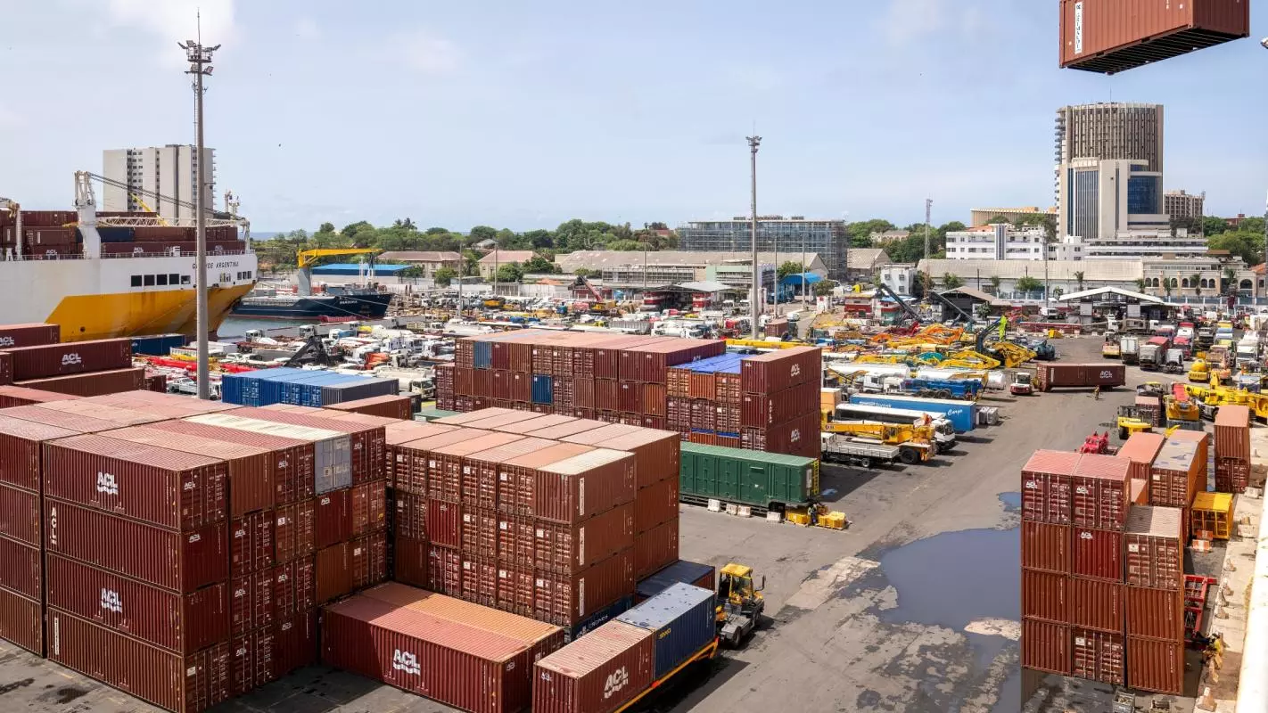 View of Dakar industrial harbour. There are rows of shipping containers and vehicles and a glimpse of a large ship in the back. Credit: manola72 - stock.adobe.com