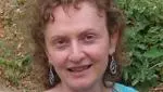 Dr Karaulashvili has curly brown hair and is wearing a bright blue dress