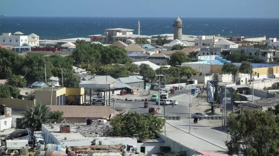An aerial shot of Mogadischu. A road runs through a town heading towards the ocean. 