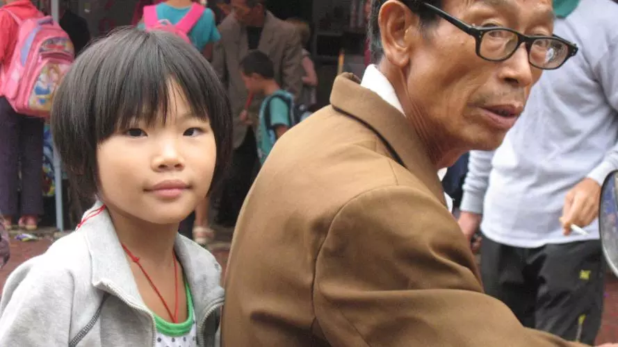 A granddaughter sitting behind her grandfather