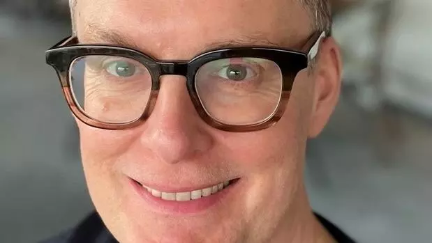 Professor paul chaisty has short dark grey hair, glasses and is smiling at the camera. He's wearing a black t shirt. 