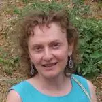 Dr Karaulashvili has curly brown hair and is wearing a bright blue dress