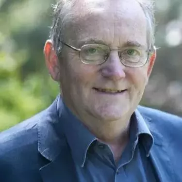 Robert has short grey hair and wearing glasses. He's wearing a blue shirt under a navy blue jacket. 
