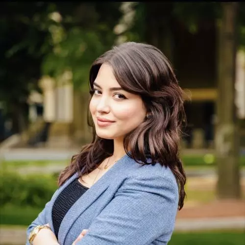 Assala Khettache has long brown hair and is wearing a blue jacket