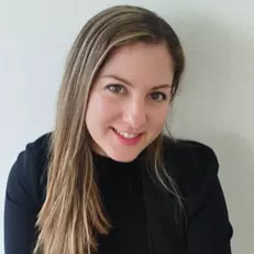 Belen has long dark blonde hair and is smiling at the camera. She is wearing a black jumper