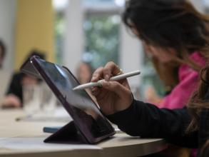 A person writing on an iPad