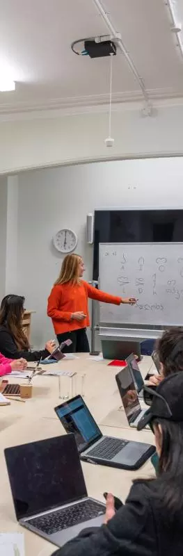 Lots of students sat around a long table in a seminar, looking towards a whiteboard.