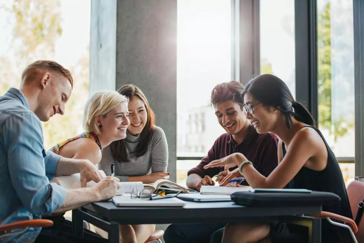 A group of students chatting around a table covered with books